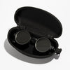 Black velvet case holding a pair of round sunglasses with adjustable dimming.