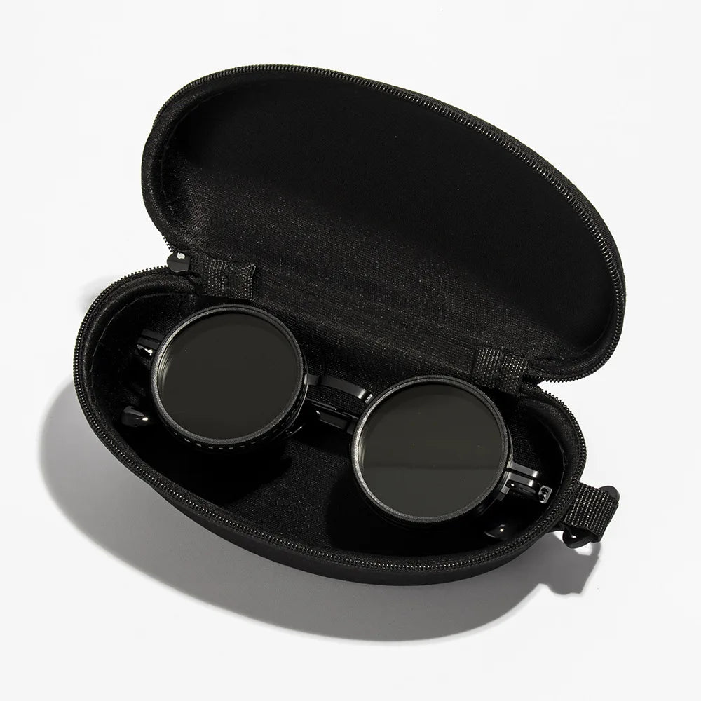 Black velvet case holding a pair of round sunglasses with adjustable dimming.
