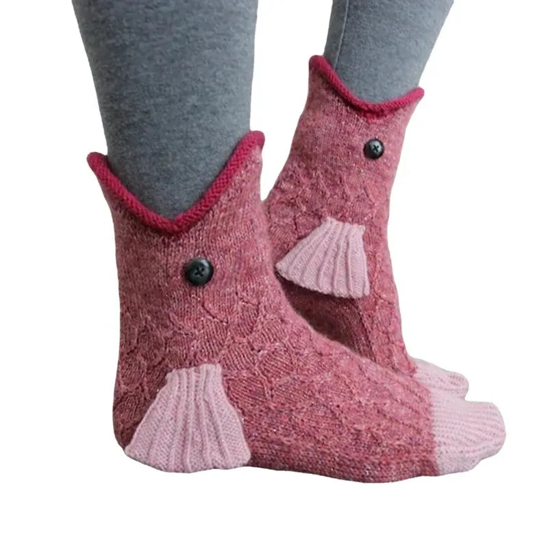 Pair of fuzzy pink knit socks with a crocodile design and red trim