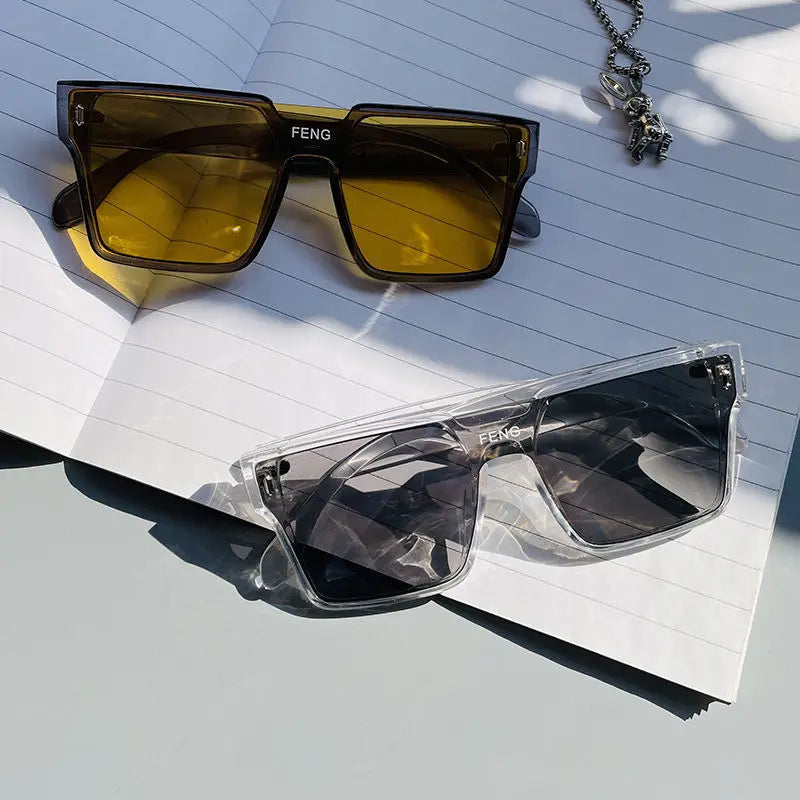 A pair of yellow-tinted, oversized square sunglasses resting on a white spiral notebook.