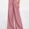 A model wearing dusty rose flowy high waist drawstring wide leg pants and a white cropped top.