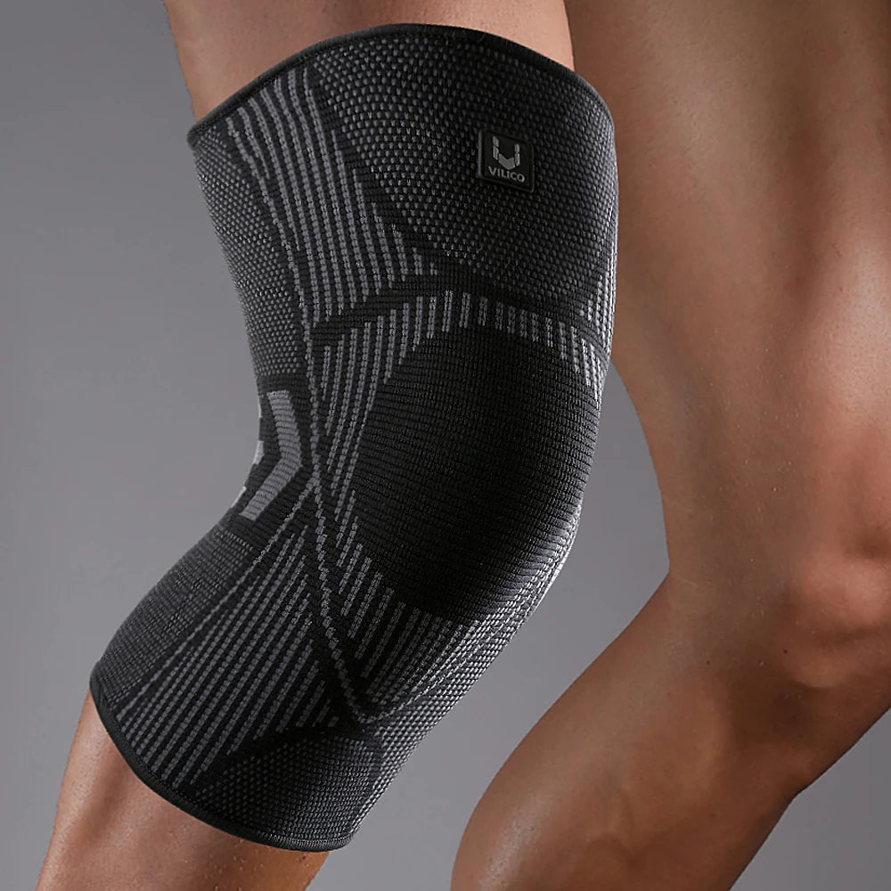 A black compression knee support sleeve worn on a person's leg.