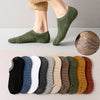 A row of men's cotton crew socks in various earthy and muted green tones displayed next to a person's foot.