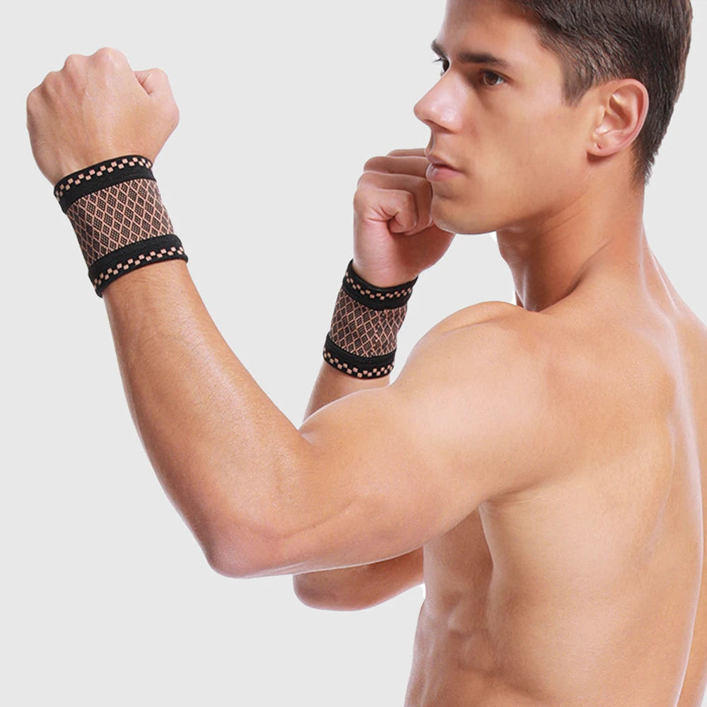 A muscular man wearing a black patterned copper compression wrist sleeve on his forearm.