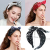 A woman models a black paisley bandana headband tied in a bow on her hair.