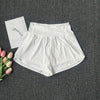 White women's high-waist yoga and fitness shorts laid flat on a dark gray surface with a white card nearby.