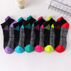 Una colección de calcetines deportivos bajos de colores en varios patrones y colores dispuestos sobre una superficie blanca.