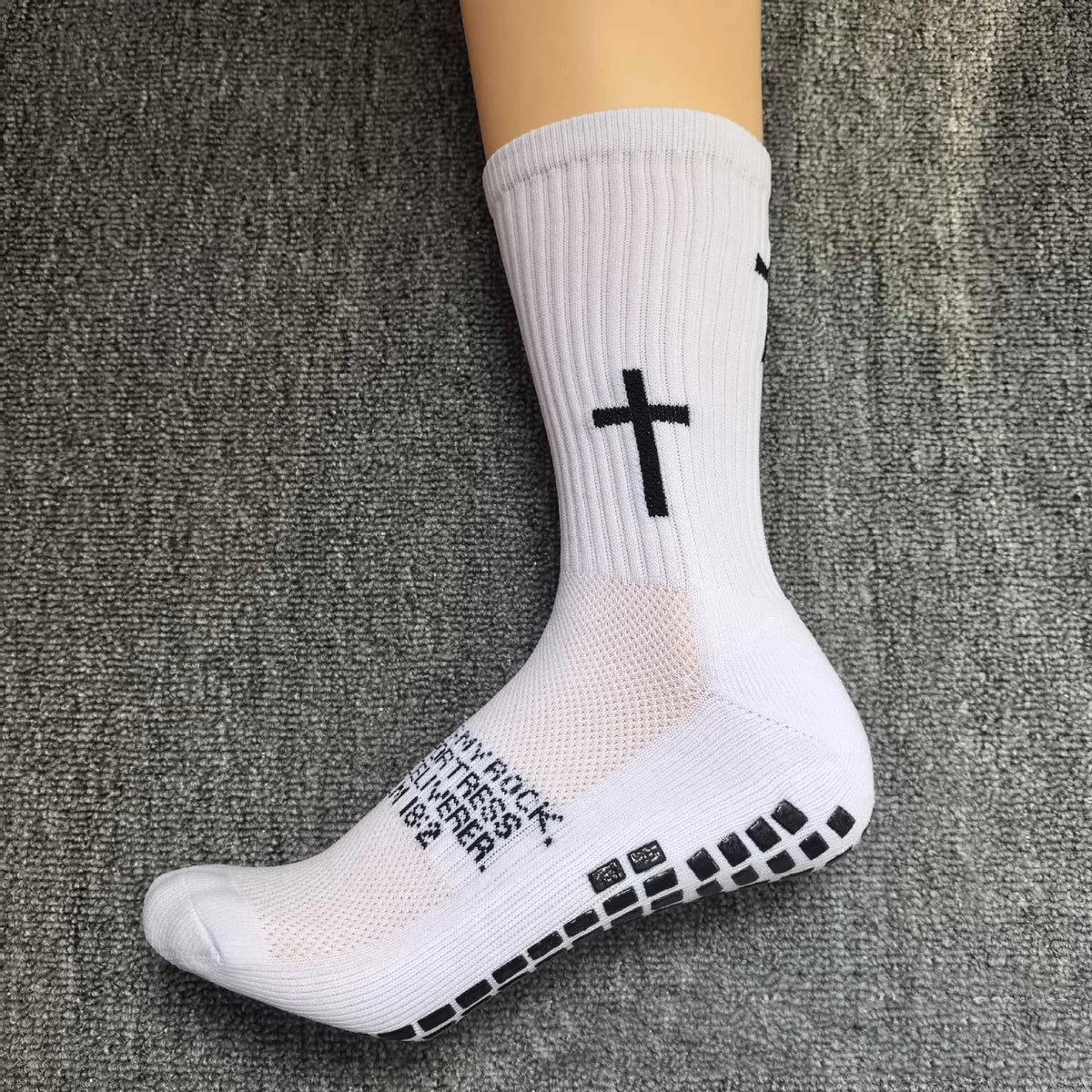 White athletic socks with a black cross design worn on a foot.