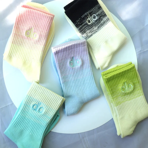 A collection of pastel colored socks featuring the 'do' logo on a white plate.