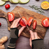 Hands wearing black knit wrist compression braces preparing fresh tomatoes on a wooden cutting board.
