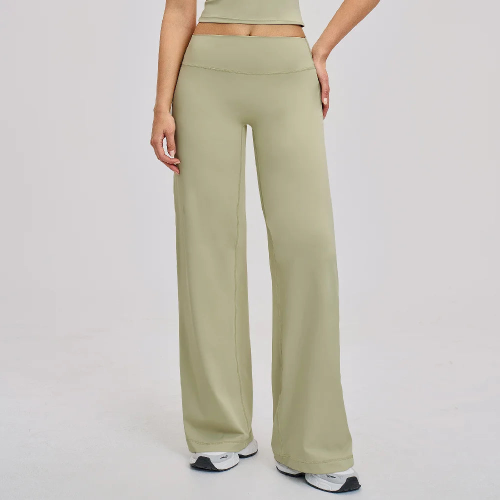 A woman wearing light olive green high-waist flared yoga pants and a matching crop top.