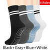 Un juego de cuatro pares de calcetines anti deslizamiento para yoga y pilates en negro, gris, azul y blanco.
