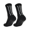 A pair of black athletic grip socks with white chevron patterns and a textured sole.