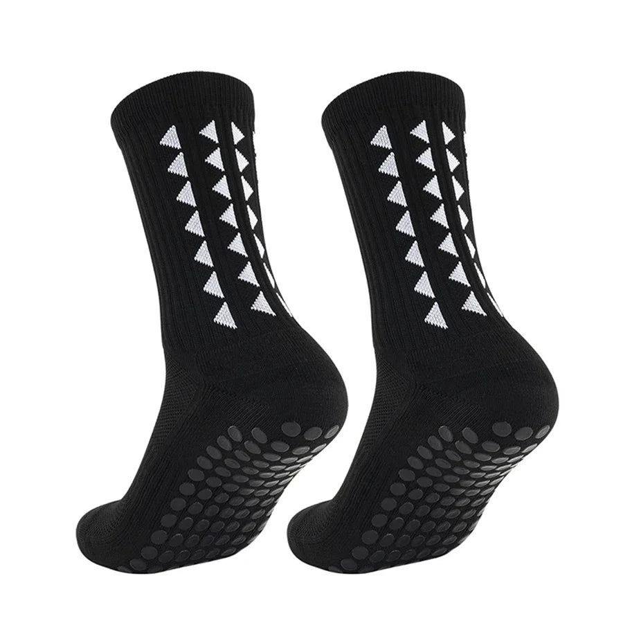 A pair of black athletic grip socks with white chevron patterns and a textured sole.