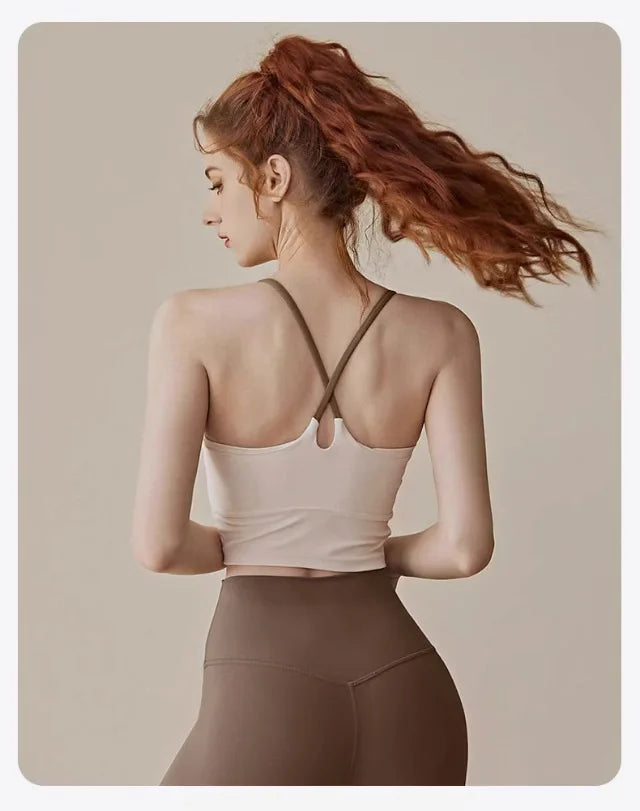 A woman with reddish hair wearing a beige supportive sports bra and matching bottoms, shown from the back.