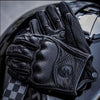 A close-up of black full finger leather motorcycle riding gloves resting on a glossy surface.