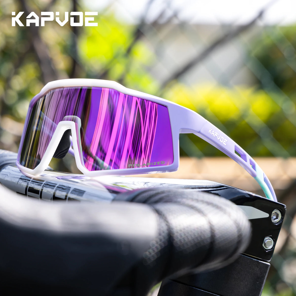 Purple and white polarized sports sunglasses resting on a bicycle handlebar.