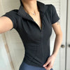 A woman wearing a black lightweight slim fit sports yoga top with a quarter zip collar.