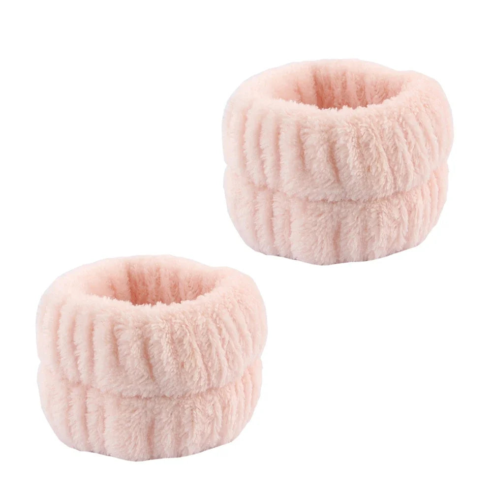 A pair of pink microfiber spa headband and wristband set with a fuzzy texture.