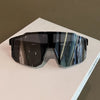 A pair of black sport cycling and skiing goggles resting on a white surface.