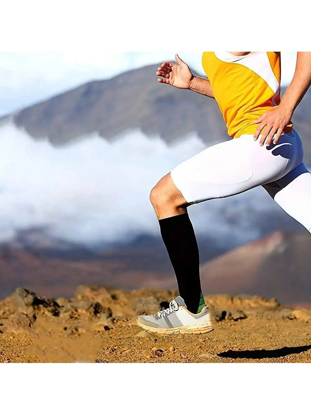 A woman wearing white athletic leggings and a yellow top is running outdoors on a rocky terrain.