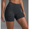 Un mannequin porte des shorts de yoga taille haute à imprimé léopard gris foncé sur fond de studio.