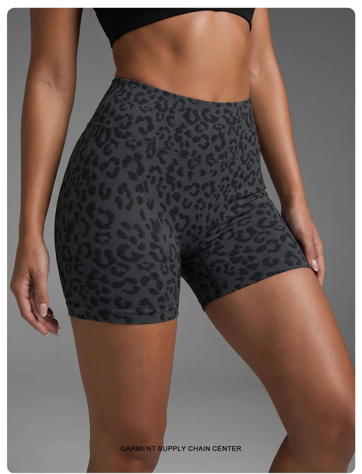 Un mannequin porte des shorts de yoga taille haute à imprimé léopard gris foncé sur fond de studio.