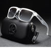 Klare, polarisierte Sonnenbrille aus Kunststoff liegt auf einer schwarzen Tasche mit silberner Schnalle.