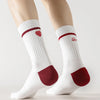 A pair of white crew socks with red accents are shown on a person's legs.