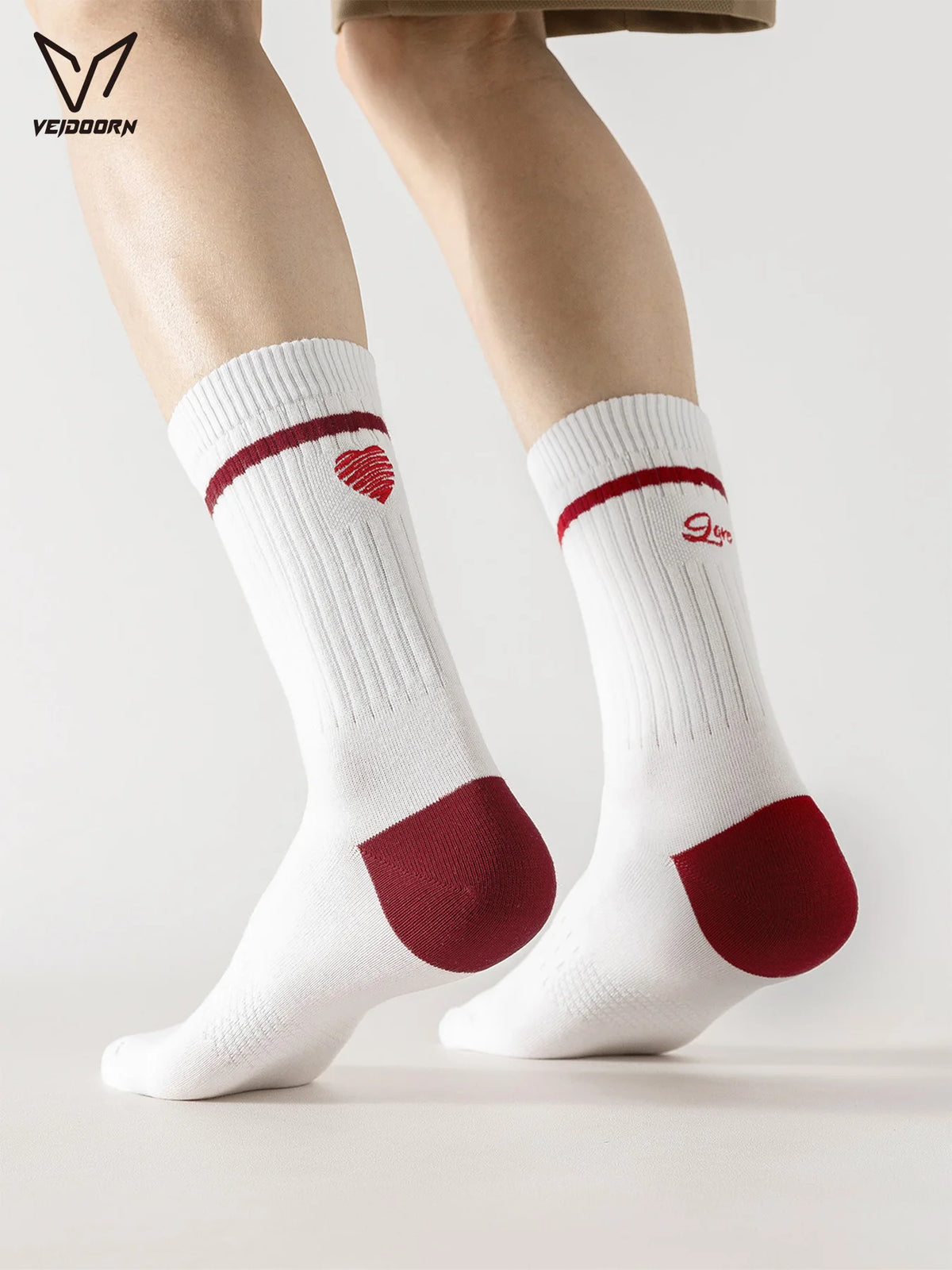 A pair of white crew socks with red accents are shown on a person's legs.