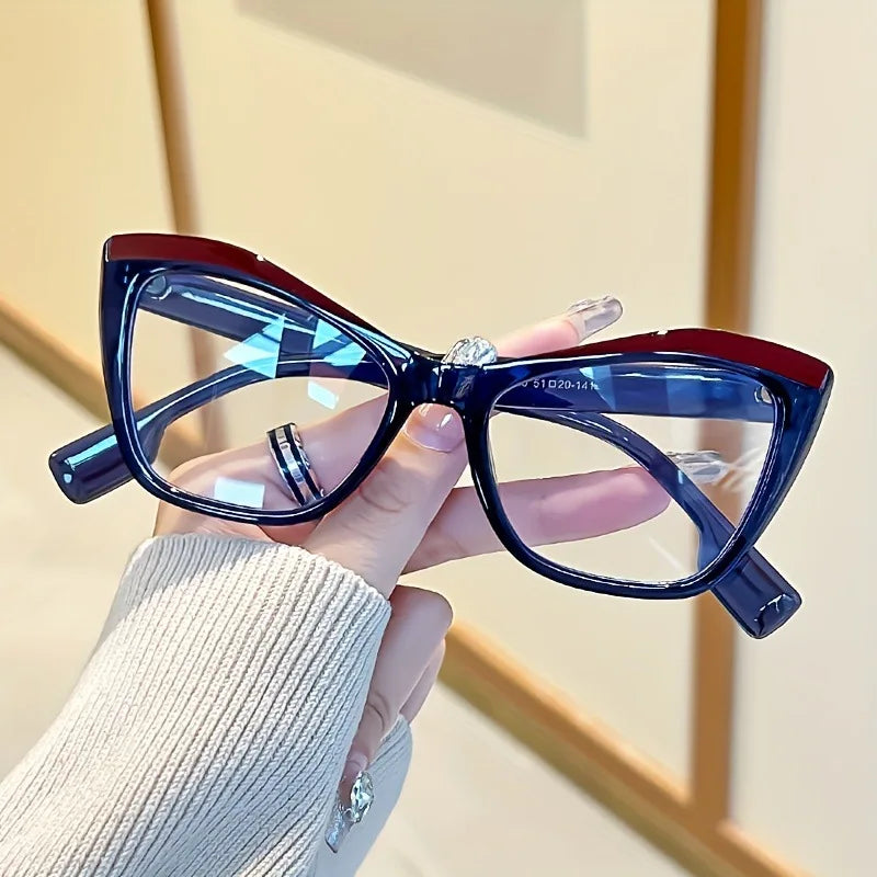 A hand holds a pair of vintage color block blue light blocking eyewear with dark frames and blue lenses.