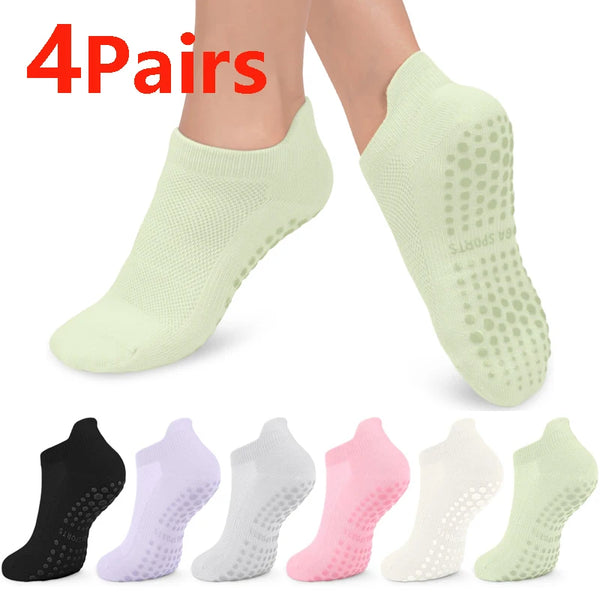 A set of four pairs of light green and pink non-slip yoga socks shown on feet.