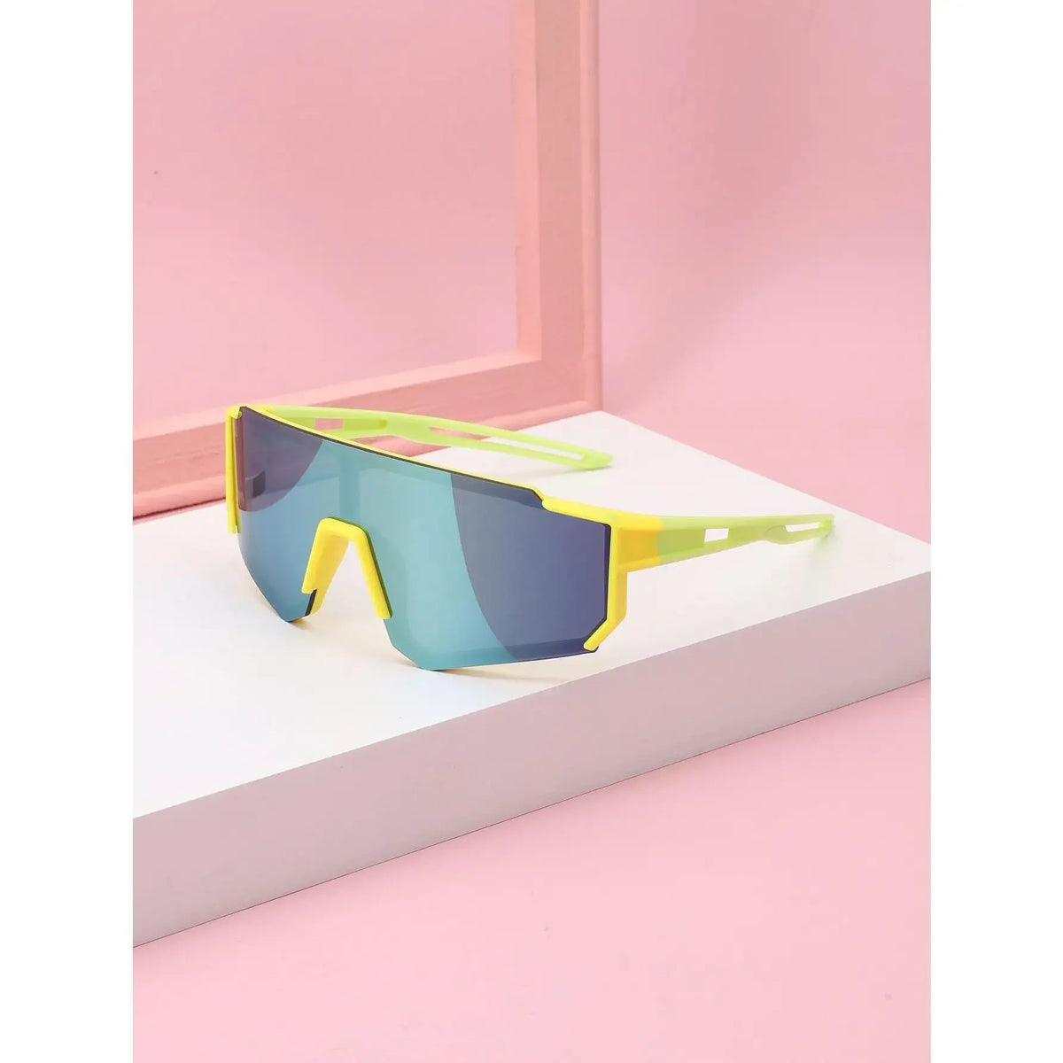 Yellow-framed kids UV protection sports sunglasses resting on a white surface against a pink background.