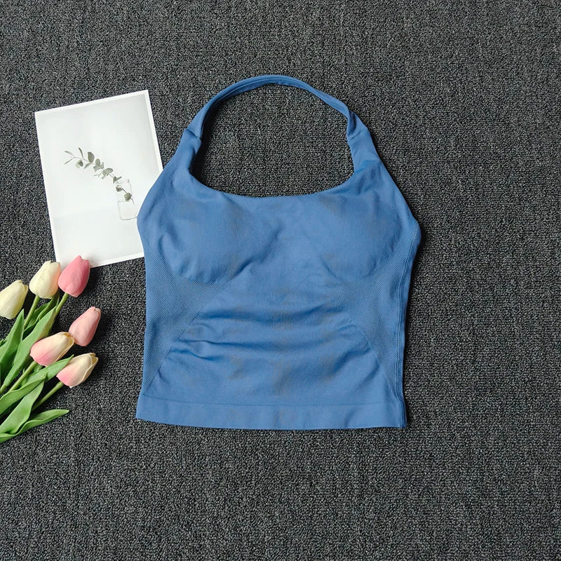 A royal blue seamless yoga and pilates sports bra laid on a dark gray fabric with pink and white flowers.
