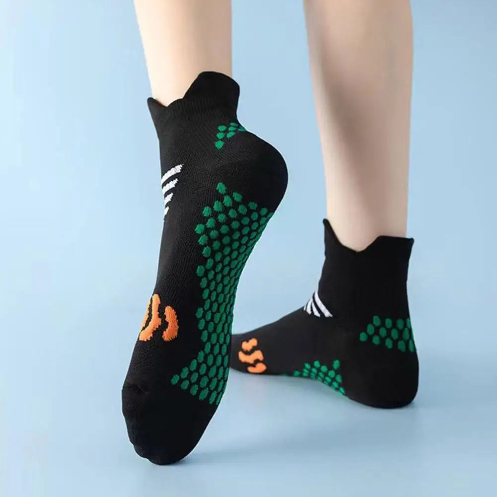 Black compression running socks with green and orange patterned details worn on a person's foot.