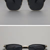 Black gold-rimmed square sunglasses shown against a gray background.