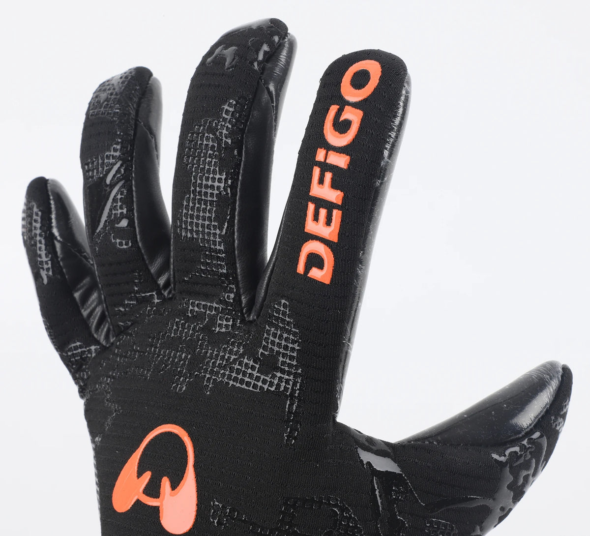 A close-up view of black Defigo goalkeeper gloves with orange accents.
