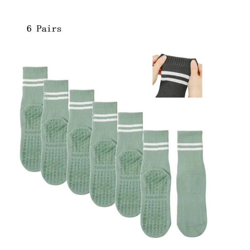 Six pairs of olive green grip socks shown in a row and a hand, suitable for Pilates, yoga, and barre.