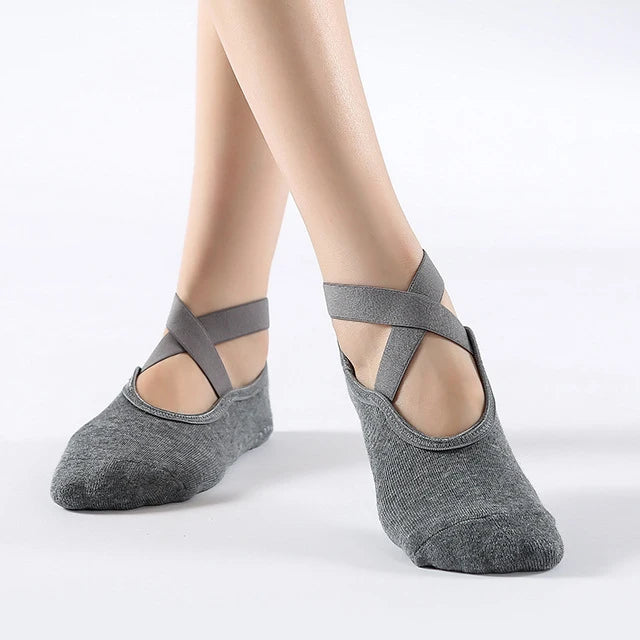 Gray breathable silicone yoga and pilates socks worn on a model's feet.