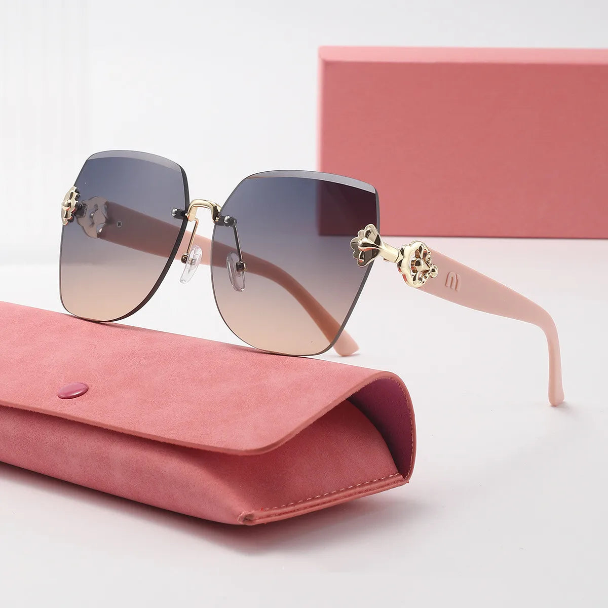Pink sunglasses resting on a pink velvet pouch next to a pink box.