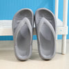 A pair of gray comfort platform flip flops resting on a white wooden surface.
