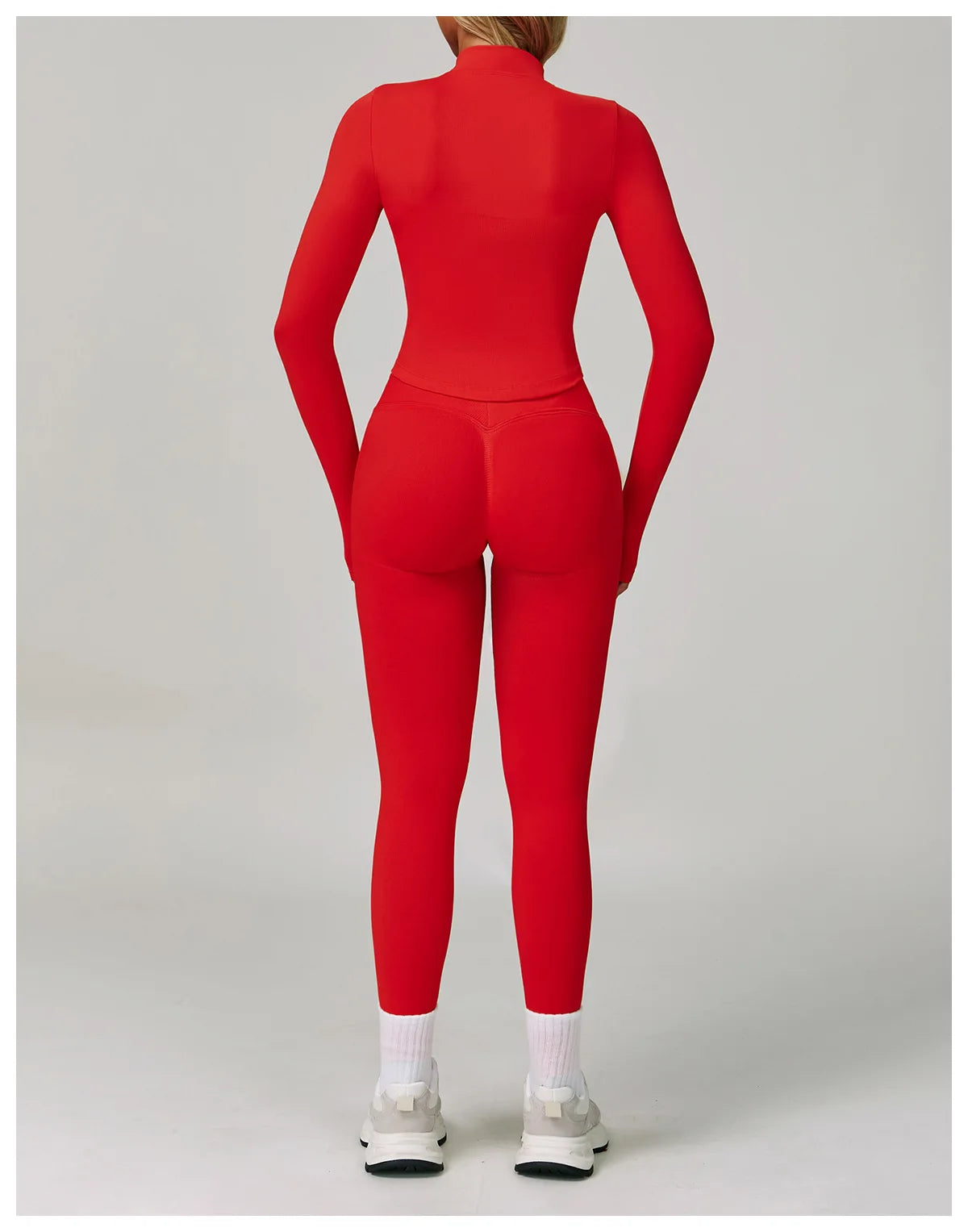 Eine Frau trägt ein rotes, nahtloses Sport-Yoga-Set mit langärmeligem Oberteil und Leggings.