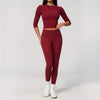 A woman wearing a long-sleeved maroon top and matching leggings set for yoga or fitness.