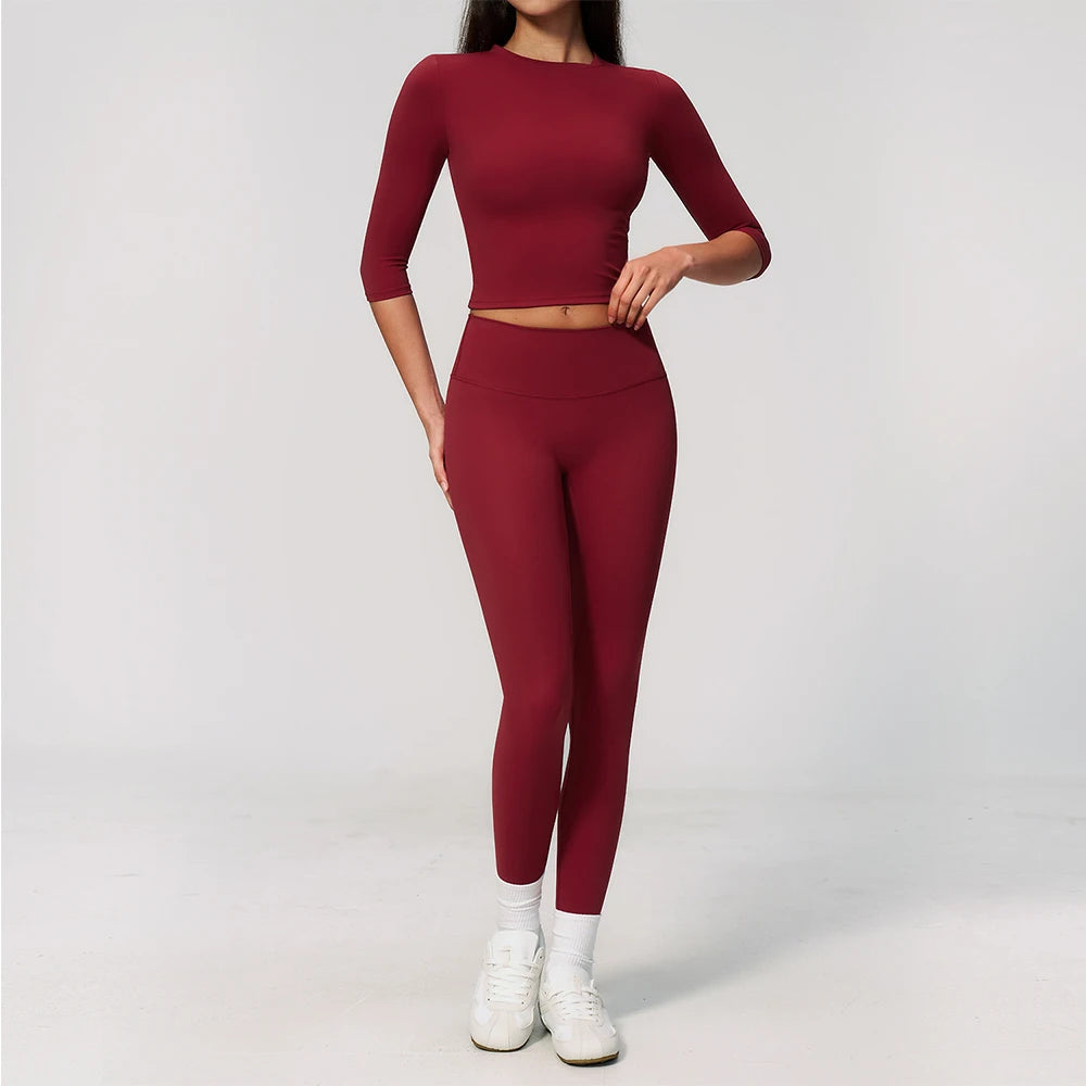 A woman wearing a long-sleeved maroon top and matching leggings set for yoga or fitness.