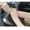 A person wearing light pink breathable arm sleeves gripping a car steering wheel.