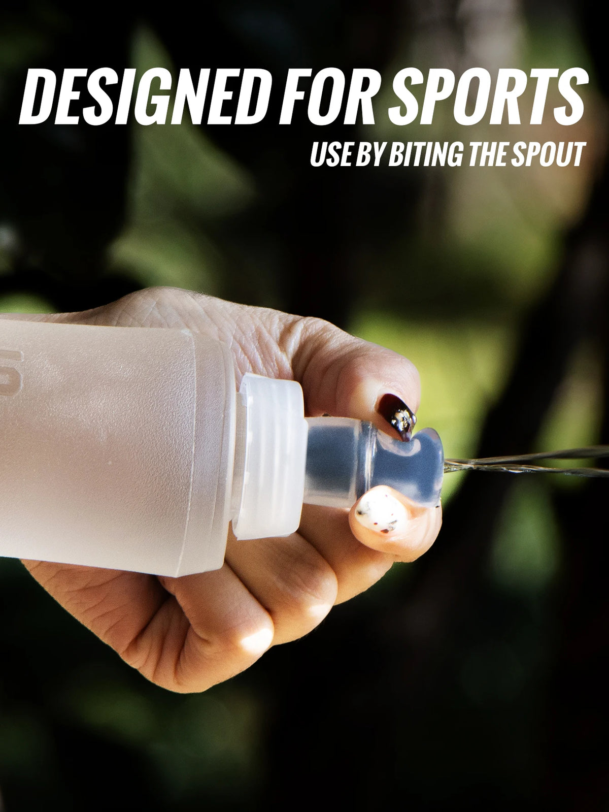 A hand holds a clear silicone hydration flask, designed for sports use, against a dark, blurred background.
