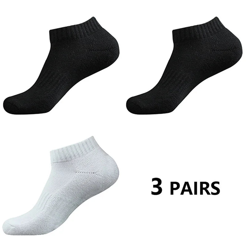 Tres pares de calcetines deportivos negros y grises de algodón para el tobillo, vistos desde el lado.