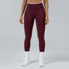 A model wearing maroon high-waist yoga leggings with white trim and white socks and white sneakers.