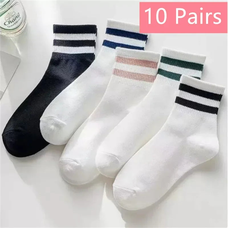 Ten pairs of white socks with black, navy blue, and pink stripes displayed on a white surface.