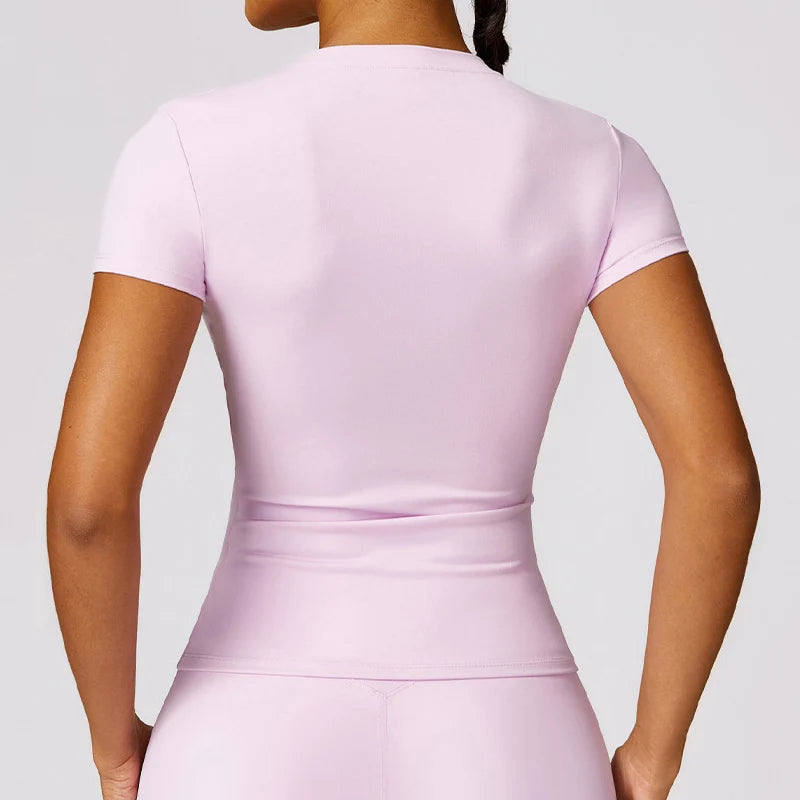 A woman wearing a light pink breathable yoga and fitness t-shirt from the back view.